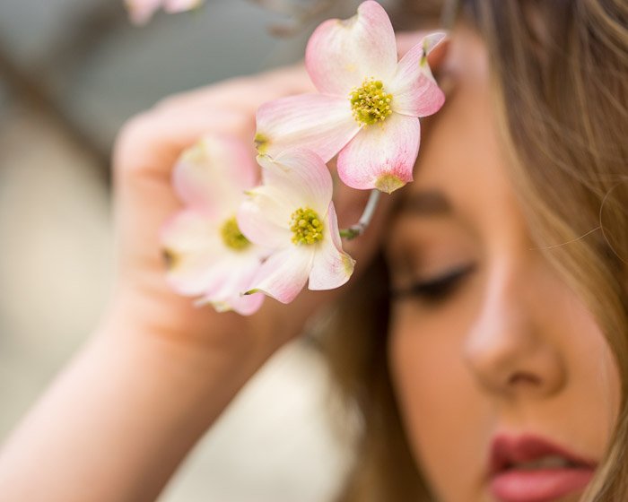 Фотография девушки, держащей розовые цветы перед лицом