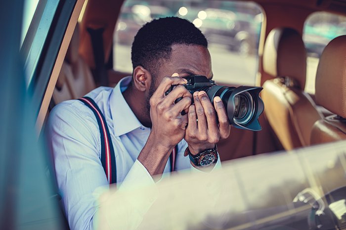 Фотограф снимает из машины с зеркальной фотокамерой.