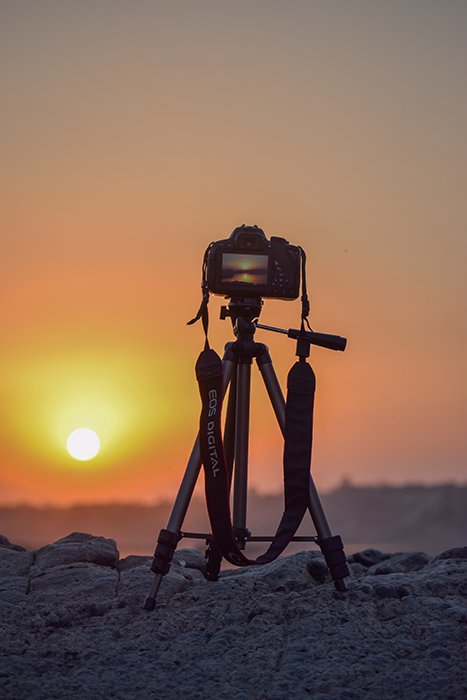 Фотография камеры на штативе на закате