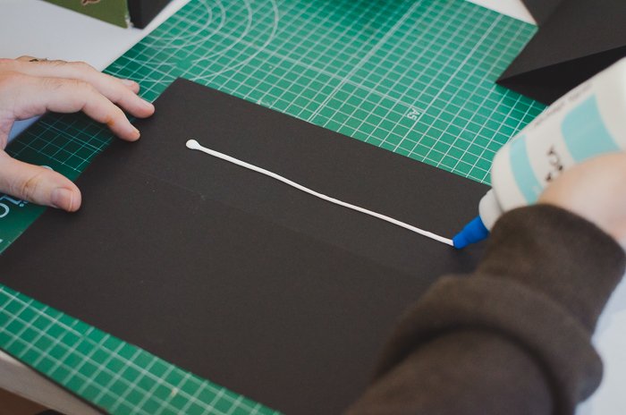 Человек клеит черную бумагу, чтобы сделать DIY-проектор