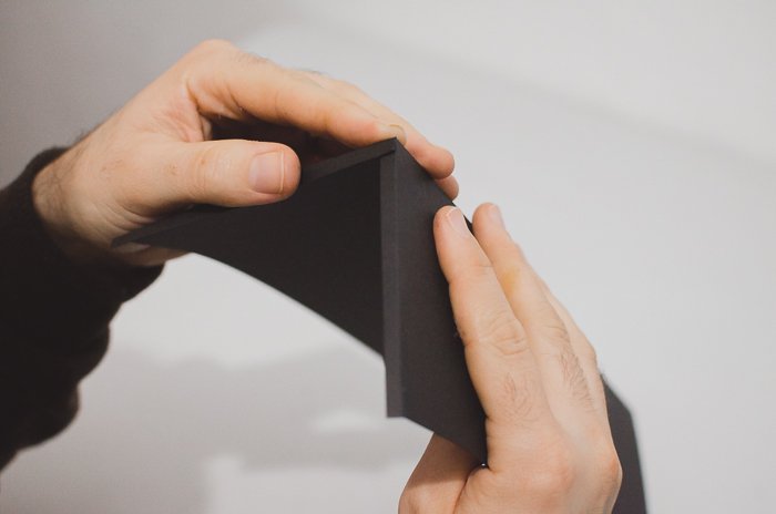 Человек складывает черную бумагу, чтобы сделать DIY проектор для объектива телефона