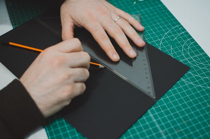 Человек режет картон, чтобы сделать DIY проектор для телефона