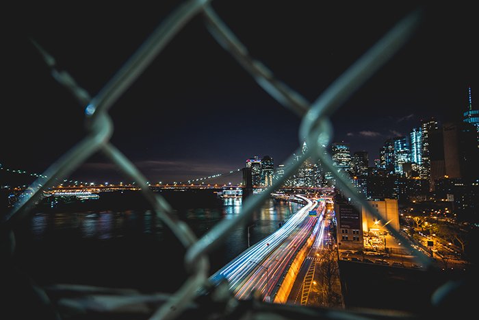 Ночной городской пейзаж, снятый через ограду из цепей