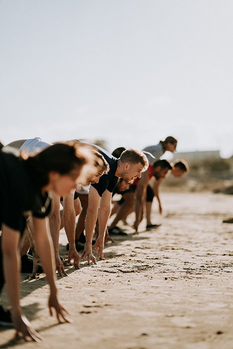Линия людей, тренирующихся на пляже