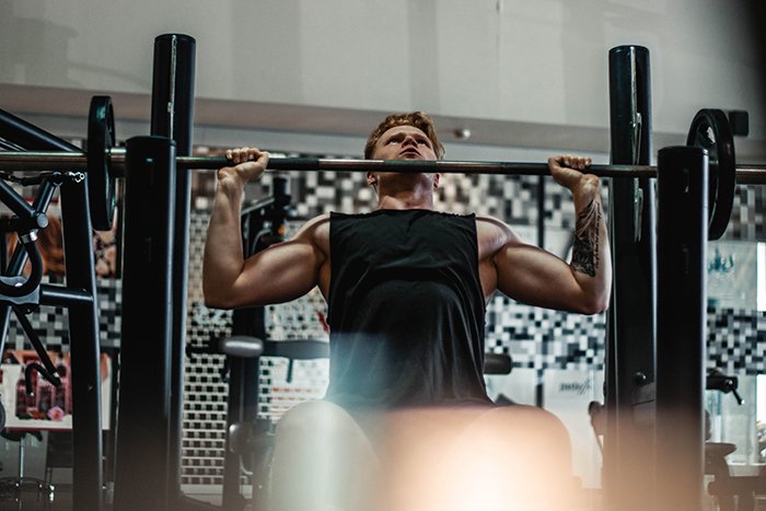 Мужчина поднимает тяжести в спортзале для фитнес-фотосессии
