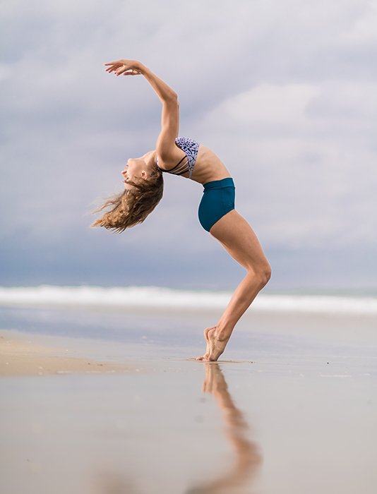 Женщина позирует на пляже для фитнес-фотосессии