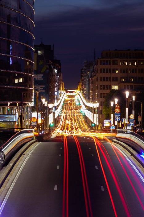 Светлые следы движения на шоссе, проходящем через ночной город