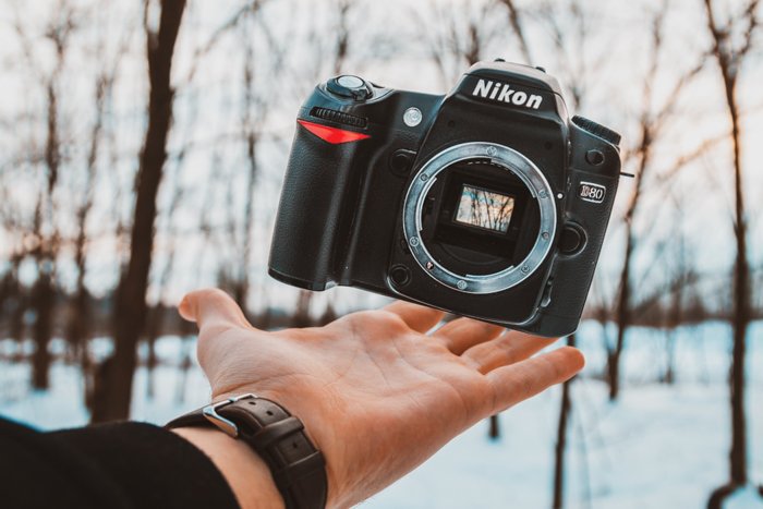 Рука, балансирующая корпус цифровой зеркальной камеры Nikon