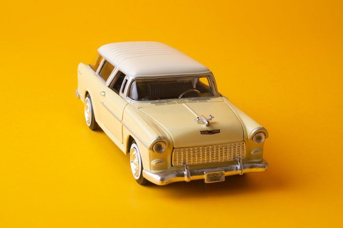 Резкое изображение игрушечного автомобиля на желтом фоне