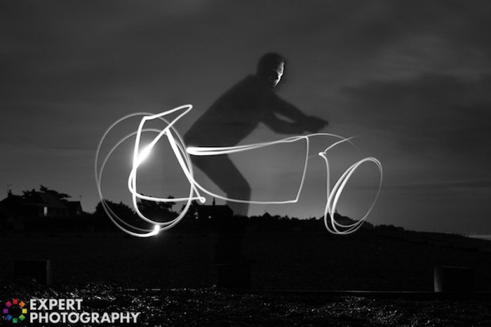 Cool night portrait of the man riding a light graffiti bike