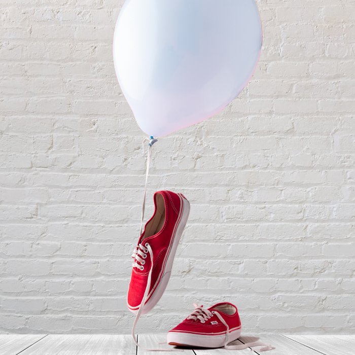 фото красных кроссовок с белым воздушным шаром и кирпичным фоном