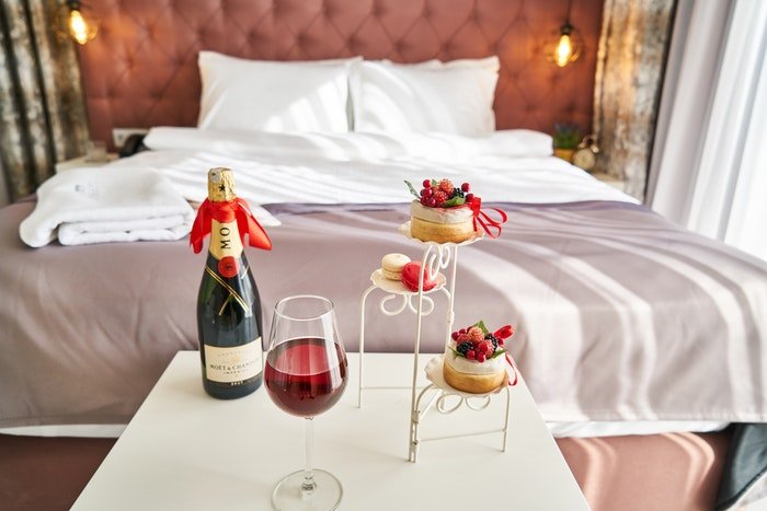 Шампанское и пирожные у изножья роскошной кровати в отеле