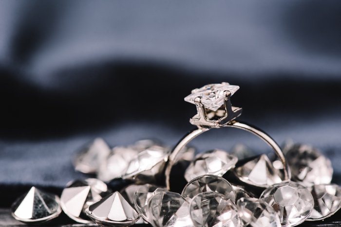 Бриллиантовое кольцо на темном фоне с другими бриллиантами вокруг него. 