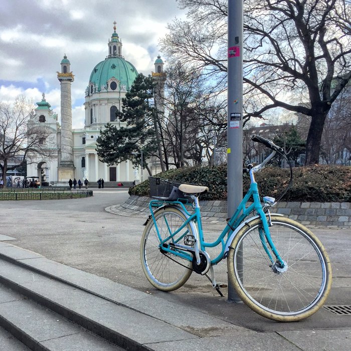 фото бирюзового велосипеда с церковью на заднем плане