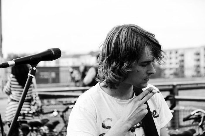 Черно-белый портрет музыканта, курящего сигарету на сцене