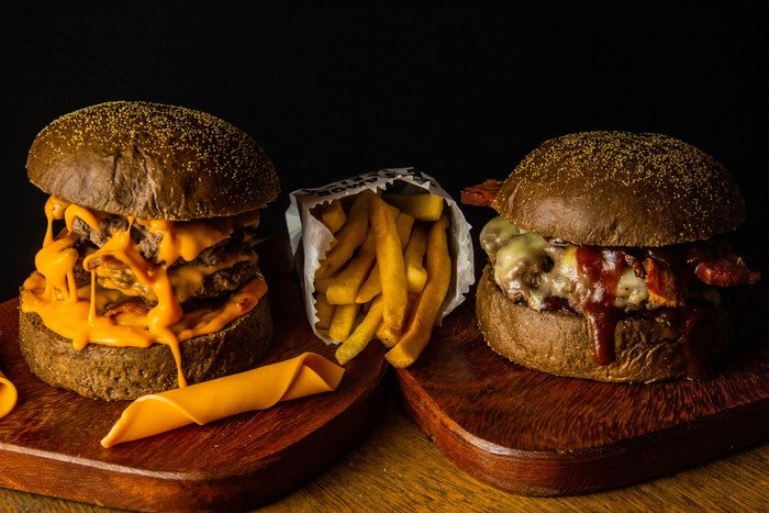 Фотография на уровне глаз двух бургеров с картофелем фри между ними