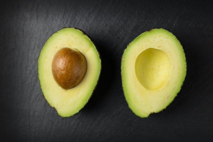 Flatlay food photo of an avocado cut in half