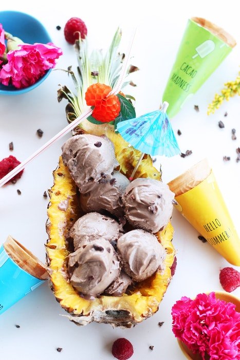 Flat lay photo of fruity ice cream served in the pineapple and ingredients