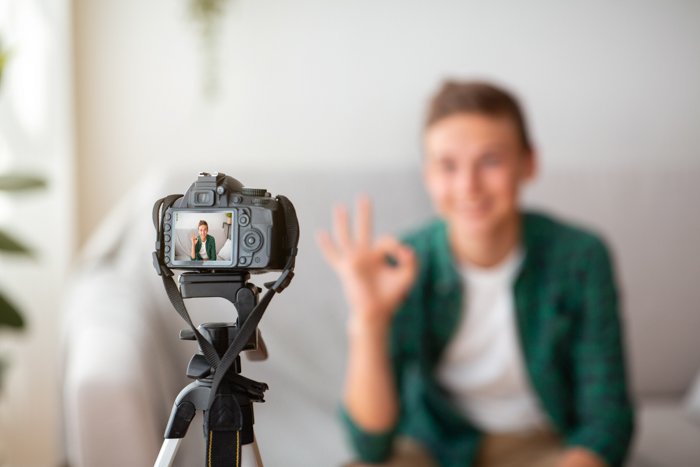 Выборочный фокус камеры, снимающей подростка, показывающего жест 