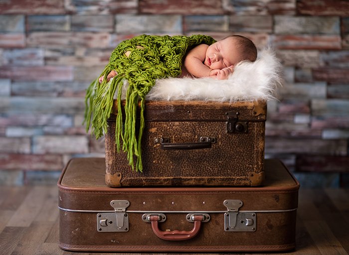Маленький новорожденный ребенок спит на деревенских чемоданах