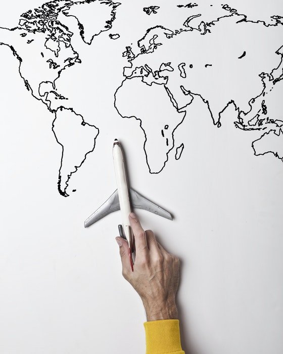 Рука, держащая модель самолета на нарисованной от руки карте мира