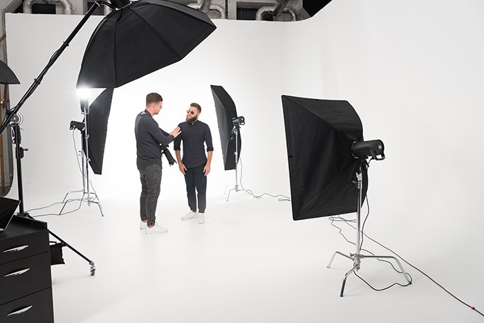 Двое мужчин стоят в фотостудии со стробоскопами.