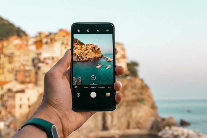 фотография человека, фотографирующего красивое побережье смартфоном