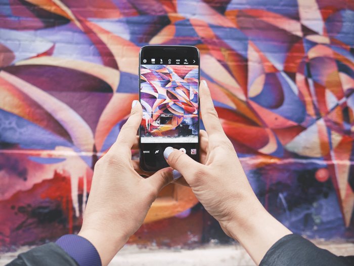 фотография человека, фотографирующего красочную стену смартфоном