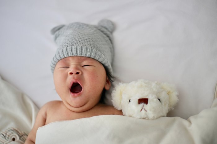 фото новорожденного ребенка в милом наряде, позирующего с плюшевым мишкой