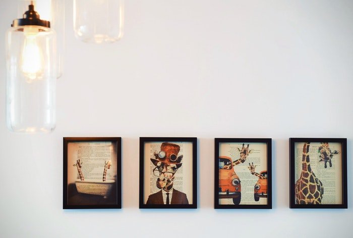 Four framed prints of quirky artwork on the wall