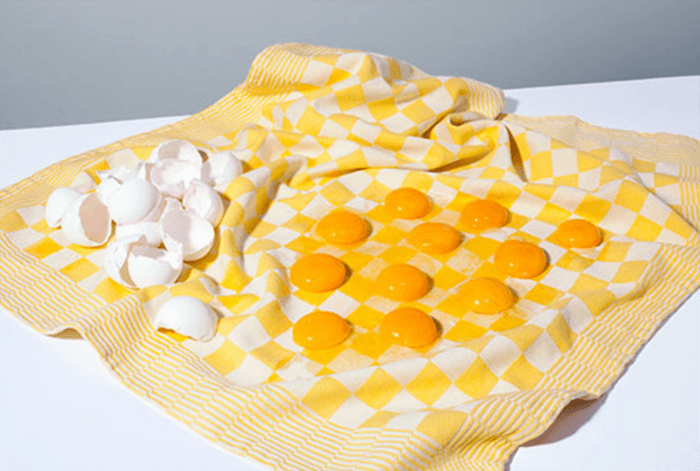 современный натюрморт фото яичных желтков, размещенных на куске ткани, напоминающем шашечную доску