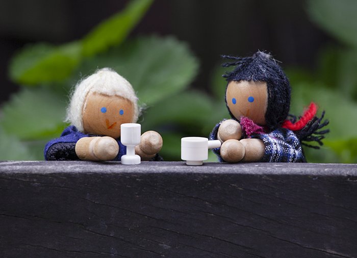 Милая игрушечная фотография двух деревянных кукол в костюмах старушек, пьющих чай