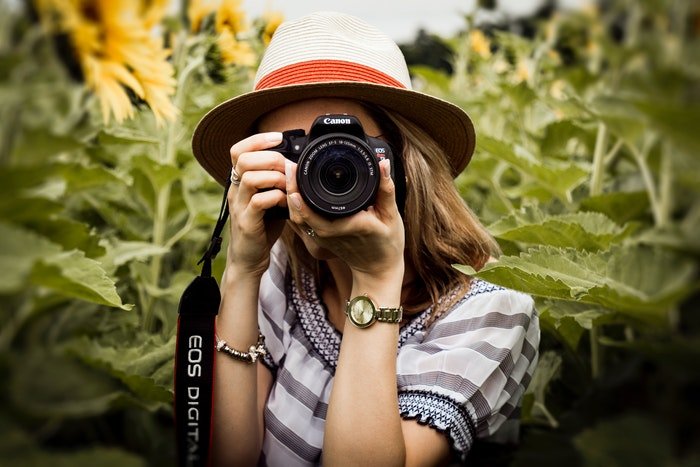 Женщина-фотограф фотографирует в поле с зеркальным фотоаппаратом Canon