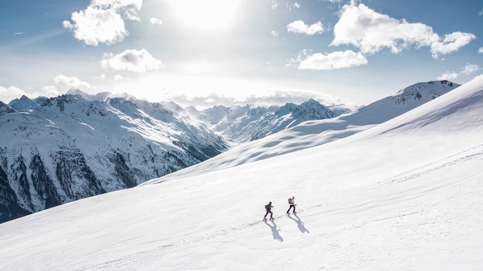 Два туриста идут по горе со сбалансированным визуальным весом гор на заднем плане