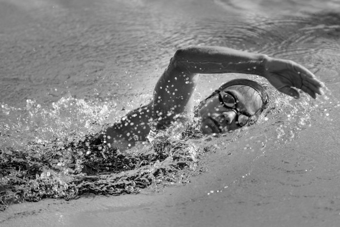 Черно-белое изображение женщины, плавающей в бассейне.