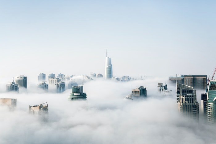 фотография городских небоскребов, проглядывающих сквозь облака