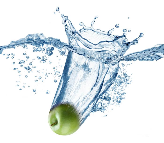 Зеленое яблоко падает глубоко под воду с большим всплеском.