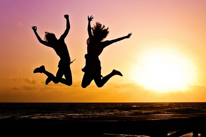 Силуэт двух девушек, прыгающих в море на закате