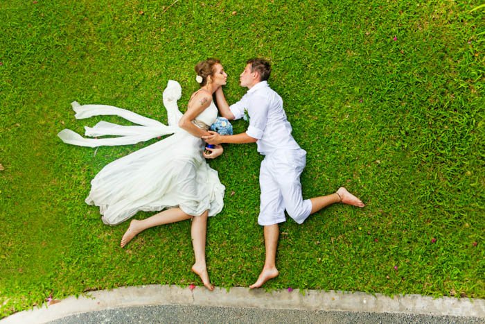 Пара лежит на зеленой траве, имитируя бросок в прыжке с угла