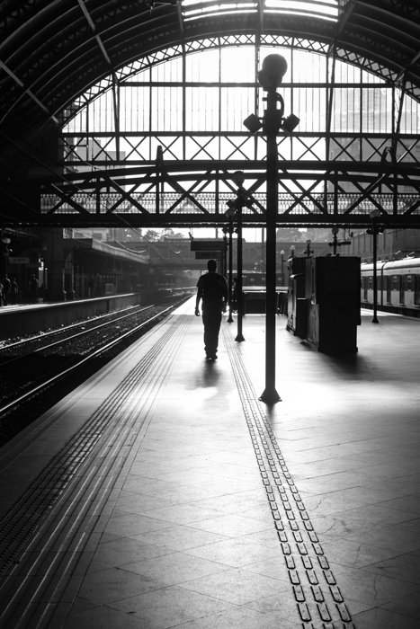 черно-белое изображение мужчины, идущего по платформе на вокзале