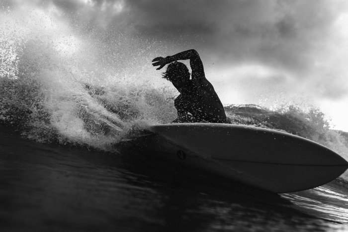 черно-белое изображение мужчины с доской для серфинга в волнах