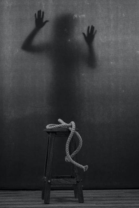 черно-белое изображение веревки на табурете и теневой фигуры на заднем плане