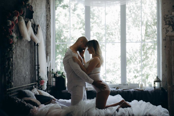 Сексуальная будуарная фотосессия пары на кровати в день Святого Валентина