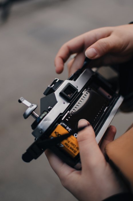 Человек загружает рулон 35-мм пленки в свою аналоговую камеру