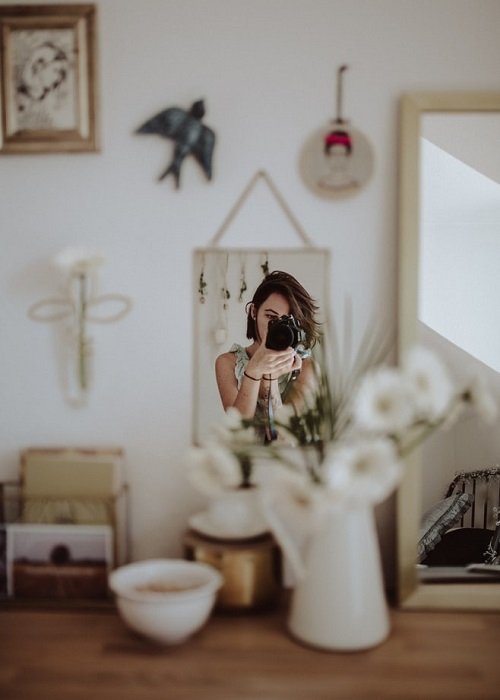 фотограф снимает изображение своего отражения в маленьком зеркале