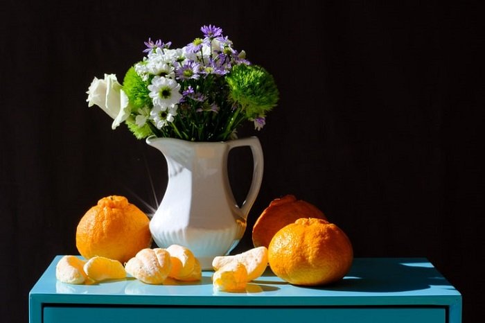 фото натюрморта из цветов в кувшине и апельсинов
