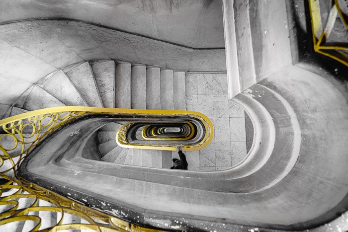 Изображение винтовой лестницы с желтыми перилами, снятое сверху после фотошопа выборочным цветом