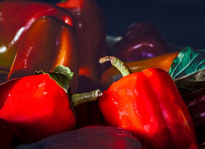 Кучи красных перцев купаются в солнечном свете на фермерском рынке после фотошопа selective color
