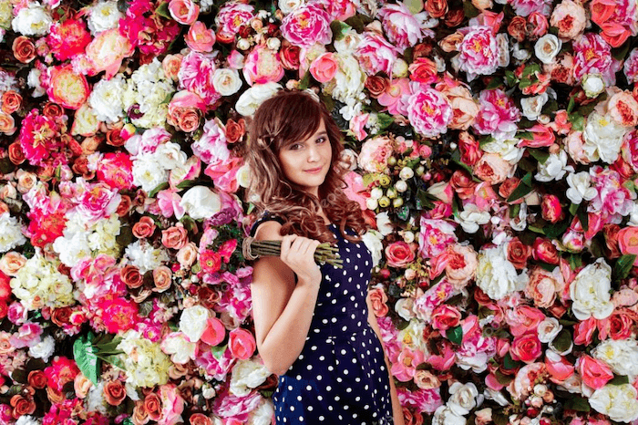 изображение молодой женщины с букетом, стоящей на фоне цветочного колодца