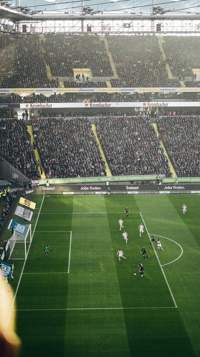 изображение футбольного стадиона с трибунами болельщиков на заднем плане